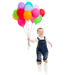 Kind mit Latzhose und bunten Luftballons in der Hand